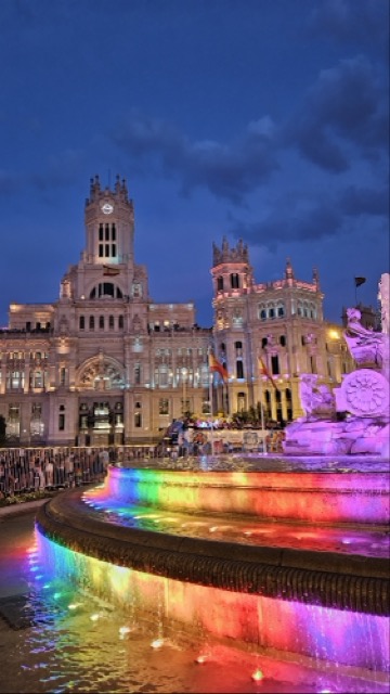 Fountain illuminated in rainbow colors during Madrid Pride.
