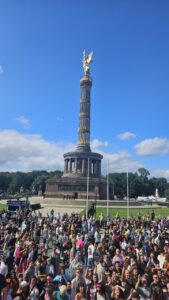 Berlin Pride parade crowds and floats with the Siegessäule (Victory Column) visible in the background during CSD Berlin