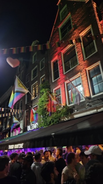 Large crowd celebrating during Amsterdam Pride on Reguliersdwarsstraat, with people filling the gay street and enjoying the festive LGBTQ+ atmosphere.