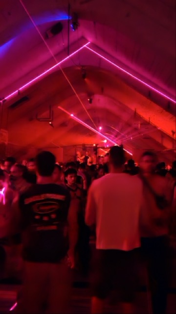 Energetic crowd dancing at a party inside a dimly lit underground club in Belgrade, Serbia.