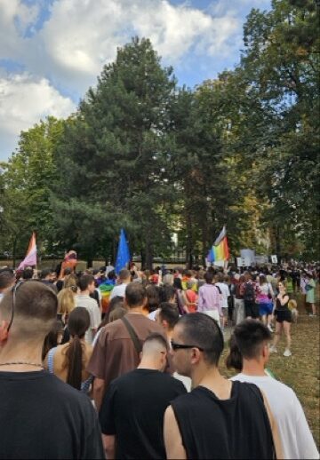 Participants gather in a park, carrying rainbow flags, walking towards the Belgrade Pride parade in Serbia.