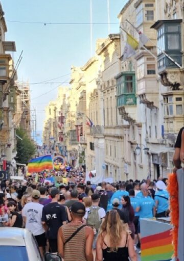 The Malta Pride parade moves through the streets of Valletta, with participants carrying rainbow flags.
