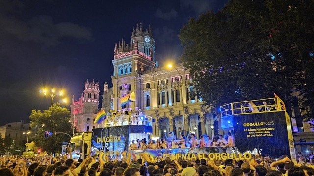 Colorful floats and crowds celebrating Madrid Pride parade at night, with rainbow lights and people dancing through the city streets.