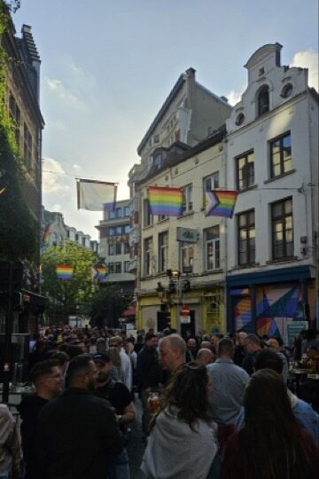 Crowds enjoying drinks on Brussels’ main gay bar street during Brussels Pride, with people celebrating LGBTQ+ pride in a lively street party atmosphere.