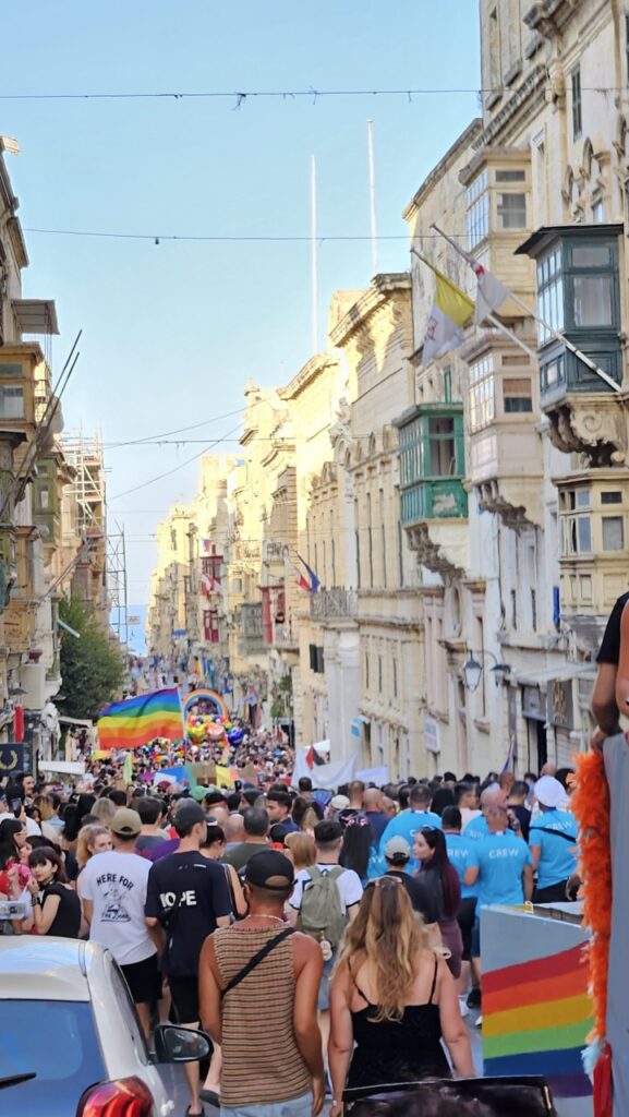 The Malta Pride parade moves through the streets of Valletta, with participants carrying rainbow flags.