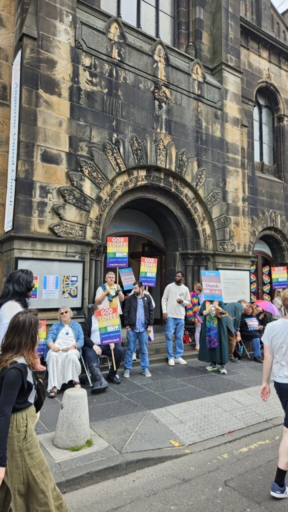 Church in Edinburgh displaying support for Pride as people gather nearby during the Edinburgh Pride celebrations.