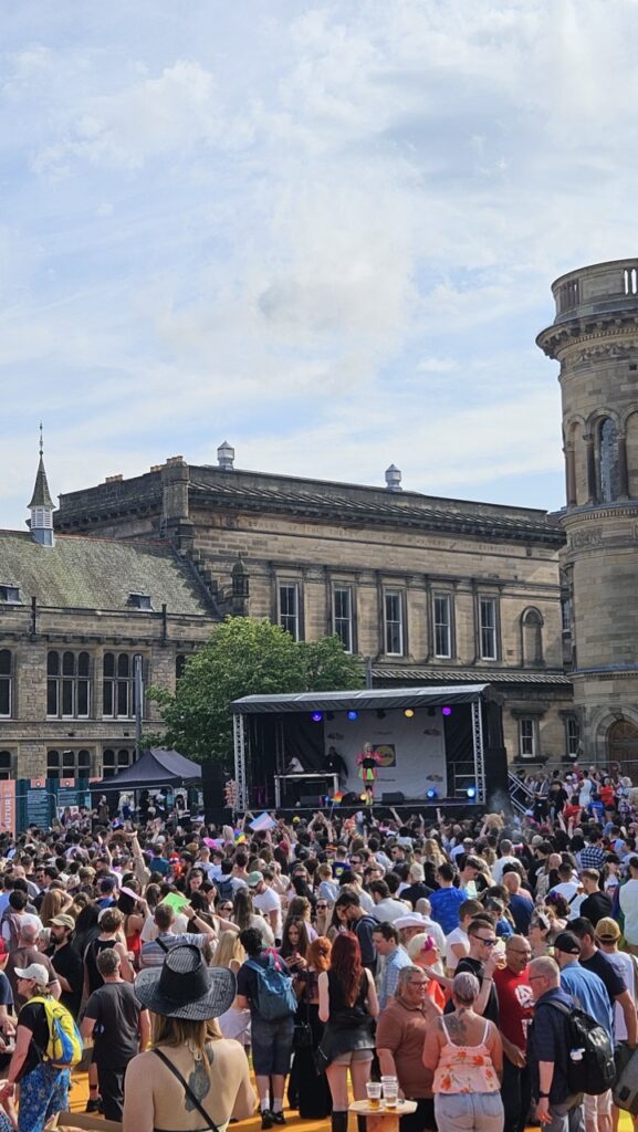 Crowd enjoying the afternoon stage party at Edinburgh Pride, gathered in front of performers celebrating LGBTQ+ pride.