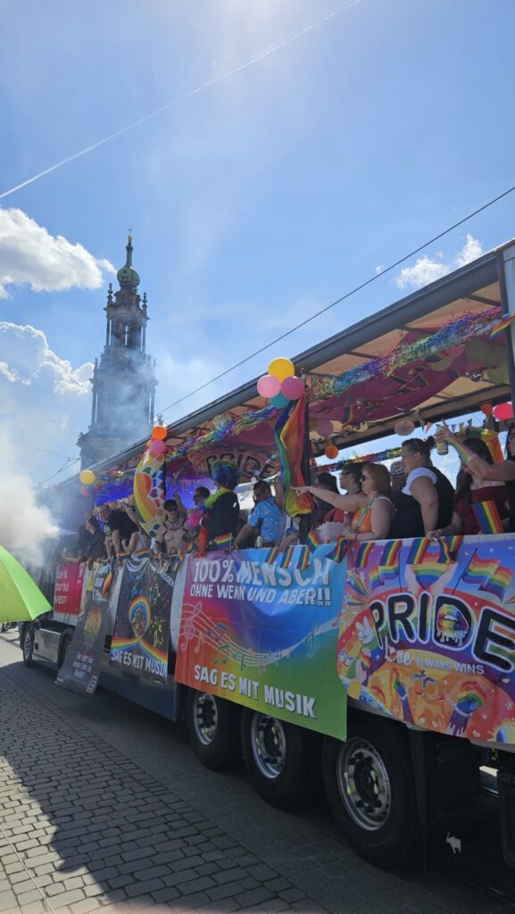 People on a colorful float during Dresden Pride parade, celebrating LGBTQ+ pride.