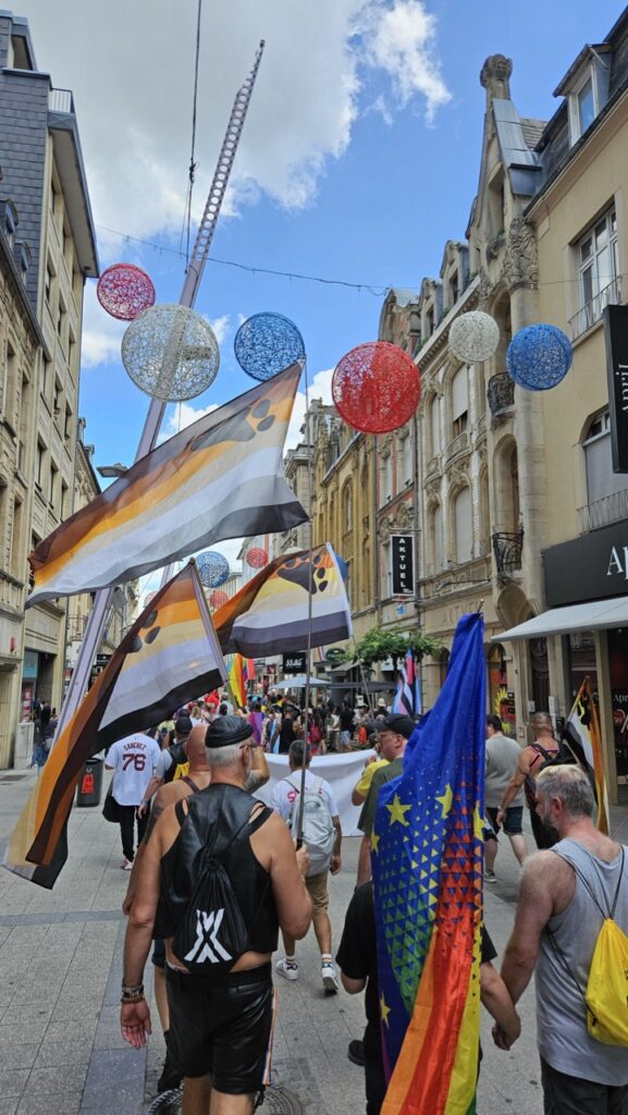 People carrying bear community flags during Luxembourg Pride, with crowds celebrating LGBTQ+ diversity in the streets.