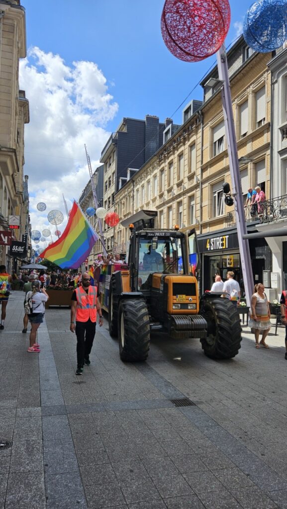 Tractor decorated with rainbow flags during Luxembourg Pride, with people celebrating LGBTQ+ pride along the parade route.