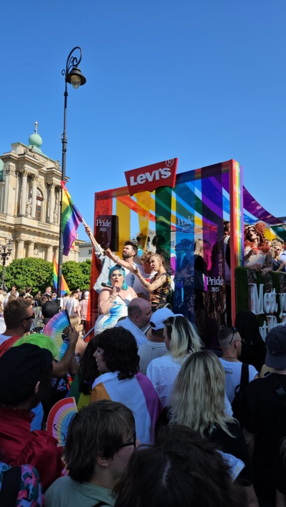A Pride truck with drag queens during Warsaw Pride, surrounded by people marching and celebrating LGBTQ+ pride.