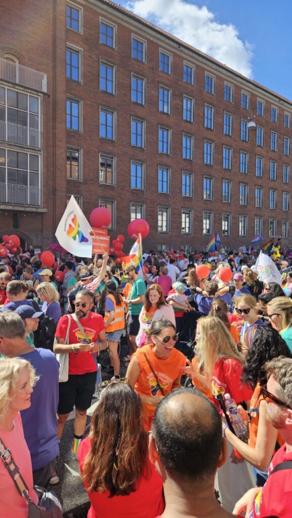Crowd gathering before the Copenhagen Pride march, with people preparing to join the LGBTQ+ parade in the city centre.