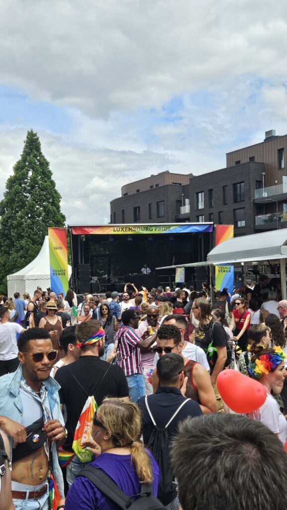 Crowd gathered at the village stage during Luxembourg Pride, enjoying a live concert and celebrating LGBTQ+ pride.