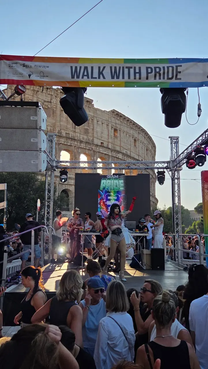 Rome Pride parade with rainbow flags at a stage next to the Colosseum in Rome